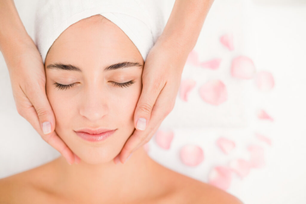 attractive woman receiving facial massage spa center