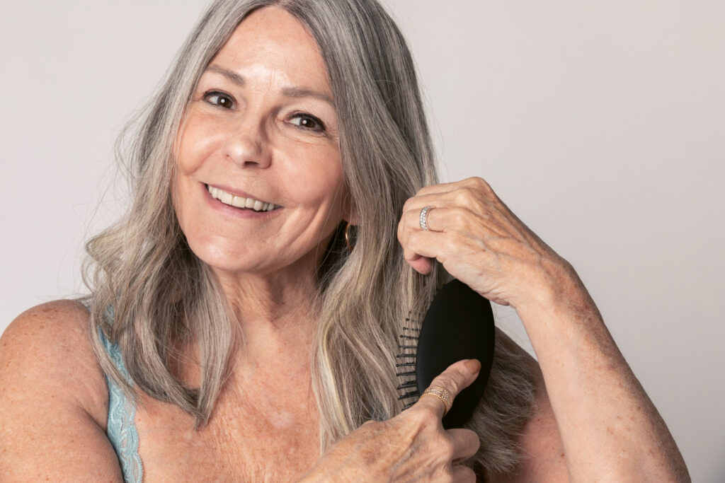 cheeful senior woman brushing her hair