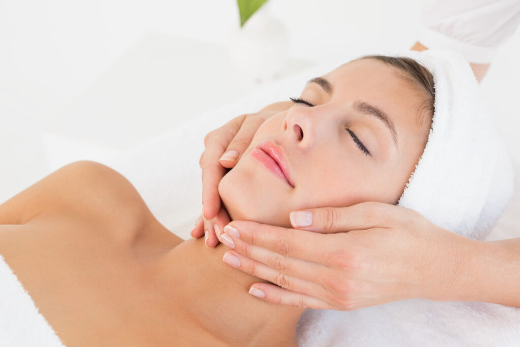 close up attractive young woman receiving facial massage spa center